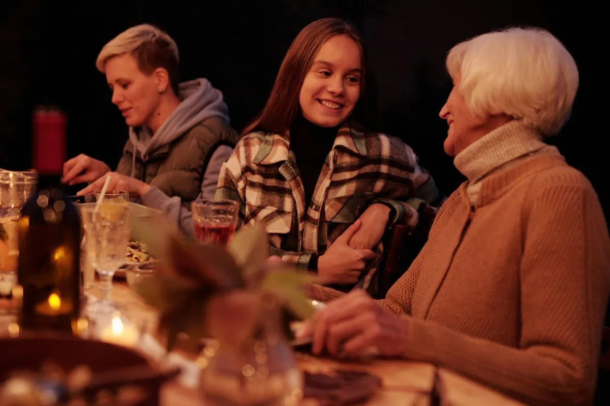 Three adults at a candlelit dinner table at home